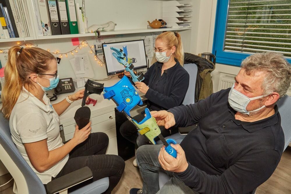 Lisa Pabst (von links) und Maria Köhlitz begutachten mit ihrem Chef Gerd Klinz in der Orthopädiewerkstatt Orthesen, die aus 3-D-Druckern stammen.