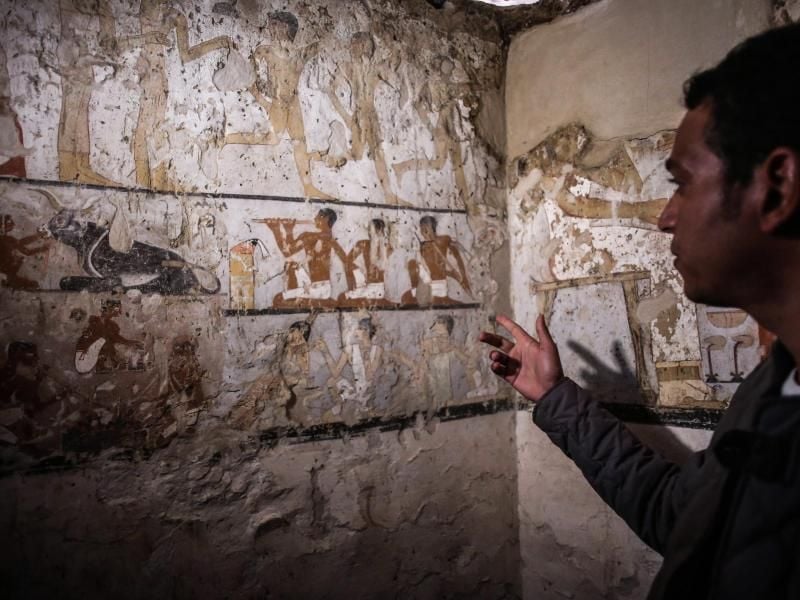 Ein Mitarbeiter der Ausgrabungen deutet auf die Wandmalereien in einem neu entdeckten Grab in der Nähe der Cheops-Pyramiden. Foto: Fayed El-Geziry
