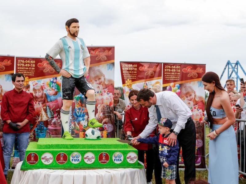 Der Bürgermeister der Stadt Bronnizy hilft einem Jungen die Geburtstagstorte von Argentiniens Nationalspieler Lionel Messi anzuschneiden. Foto: Ricardo Mazalan/AP