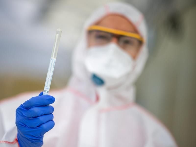 Ein Mitarbeiter hält in einem Abstrichzentrum einen Coronatest-Abstrich in der Hand. Foto: Sebastian Gollnow/dpa/Symbolbild