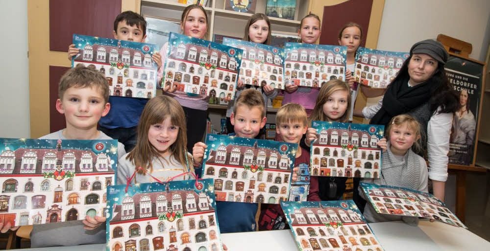 Projektleiterin Claudia Faust (r.) und die Kinder aus dem Salztorhort präsentieren die Kalender.