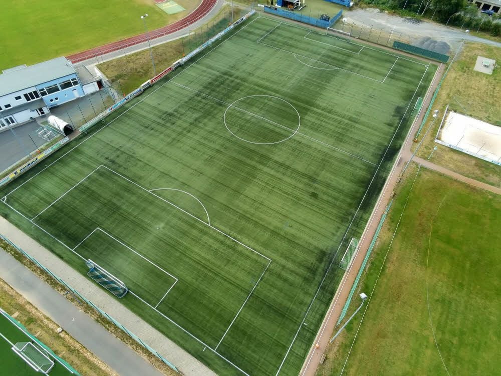 Einer der beiden Kunstrasenplätze im Sangerhäuser Friesenstadion. An den Rändern sind Ansammlungen des schwarzen Granulats zu erkennen.