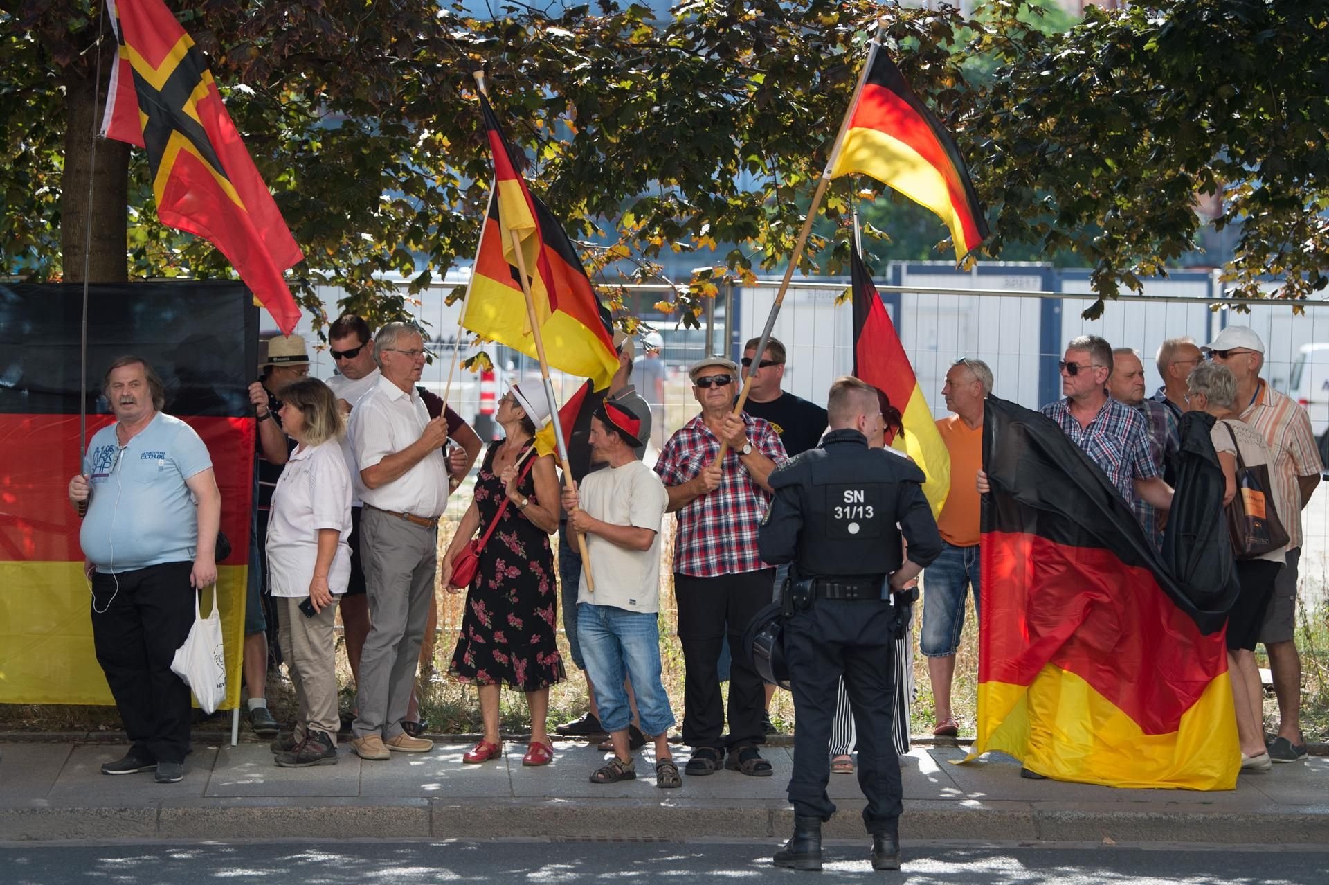 Teilnehmer einer Demonstration der islamfeindlichen Pegida-Bewegung stehen anlässlich des bevorstehenden Besuchs von Bundeskanzlerin Merkel (CDU) im Sächsischen Landtag an einer Straßenkreuzung.