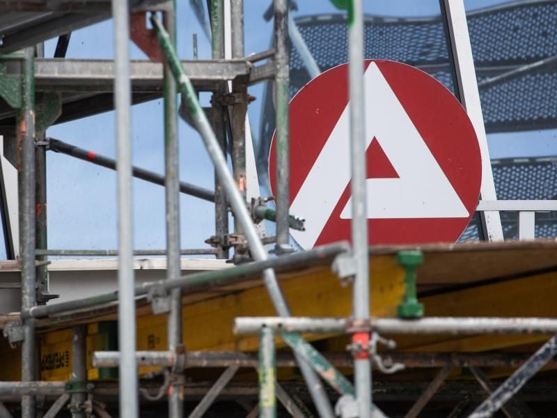 Das Logo der Agentur für Arbeit hinter einem Baugerüst. Foto: Daniel Karmann