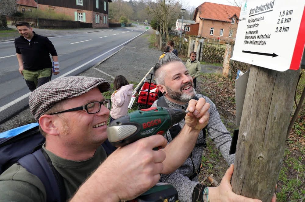Robert Henning (links) und Stephan Krimmling vom Harzklub-Zweigverein Bad Suderode bringen am Haferfeld ein neues Schild an, das Wanderern den richtigen Weg zeigt.