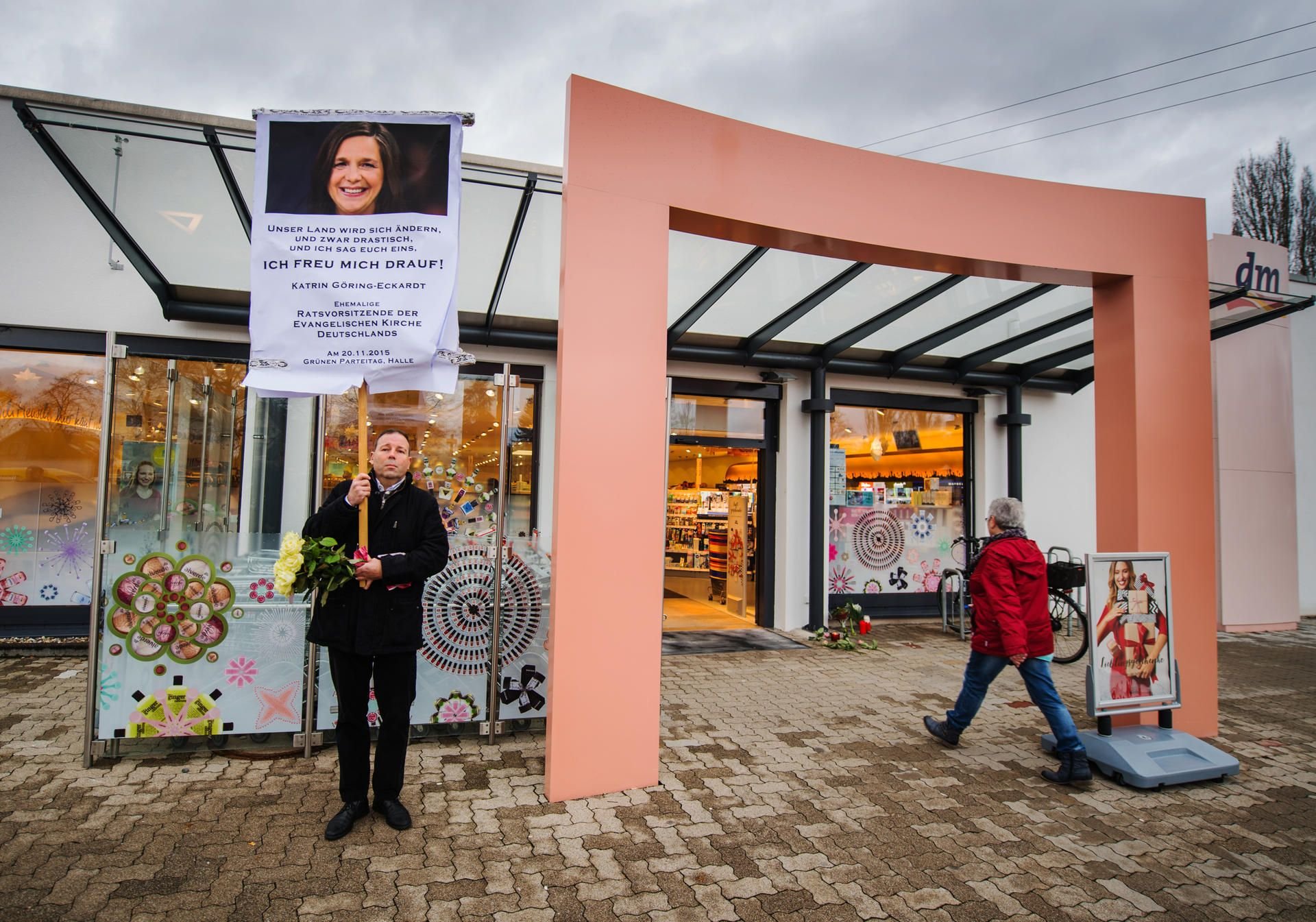 Ein Mann bringt mit einem Schild seinen Unmut über die aktuelle Politik am vor dem Drogeriemarkt in Kandel (Rheinland-Pfalz) zum Ausdruck.
