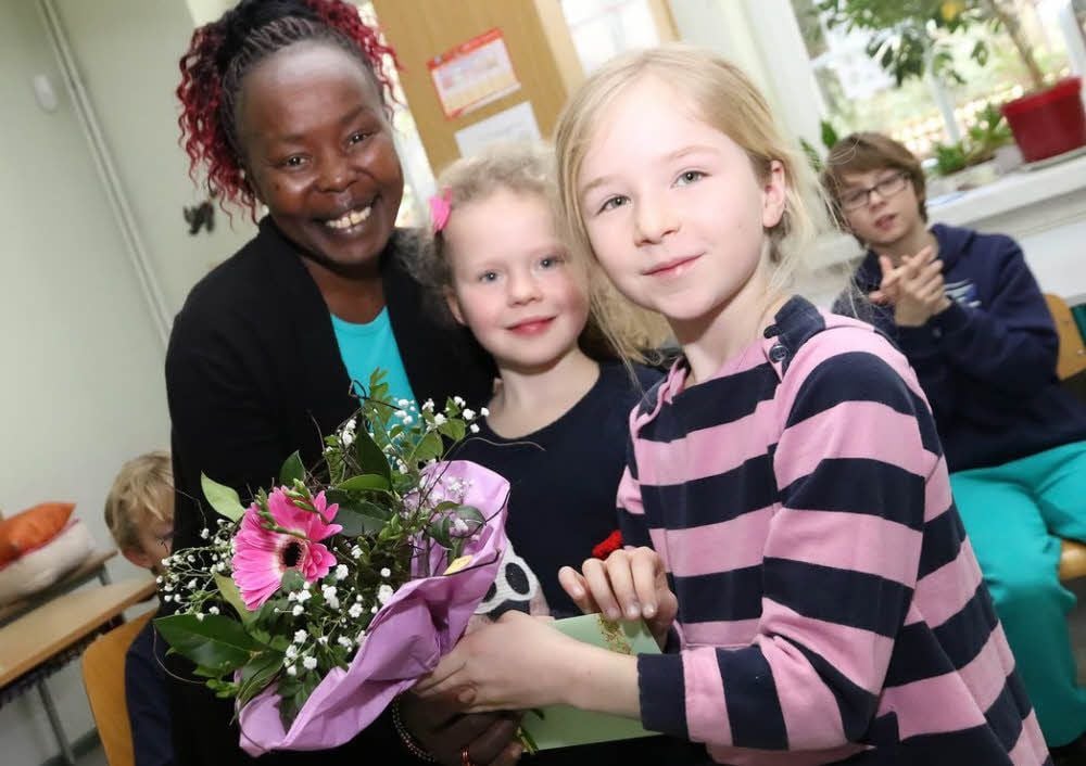 Tegla Loroupe wird von den Kindern Annalena und Ronja (rechts) mit einem Blumenstrauß in der Grundschule in Heiligenthal begrüßt.