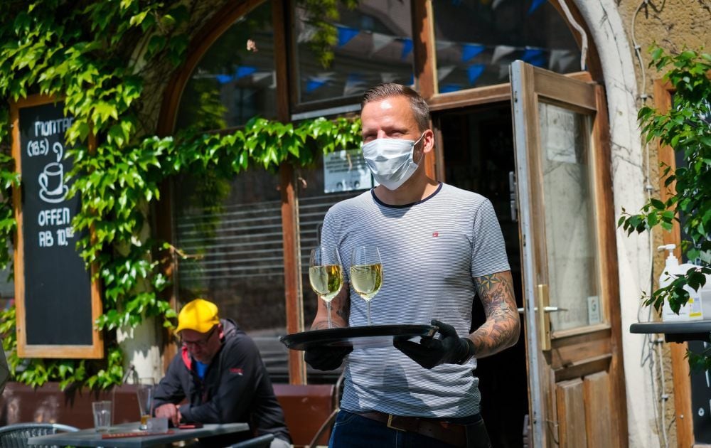Mit Handschuh und Mundschutz: „Nöö“-Wirt Martin Zachura bedient Gäste.