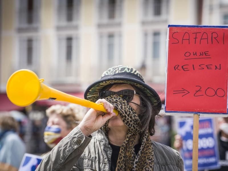 Eine Frau mit Safarihut und einer Vuvuzela steht bei einer Demonstration am Römer. Foto: Frank Rumpenhorst/dpa