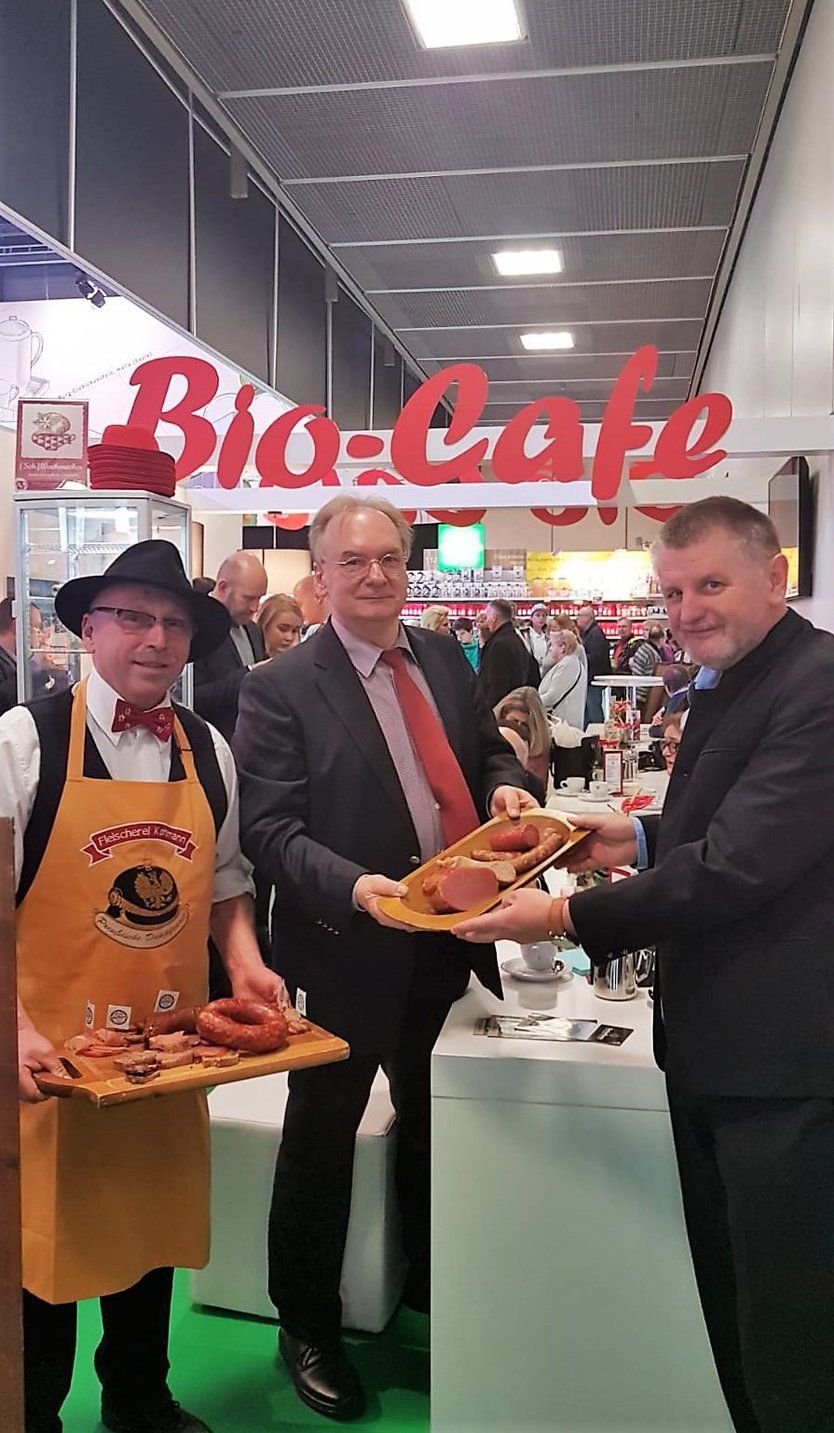 Ministerpräsident Reiner Haseloff (Mitte) und Landrat Uwe Schulze probieren die Wurst von Fleischermeister Kohlmann aus Greppin (l.).