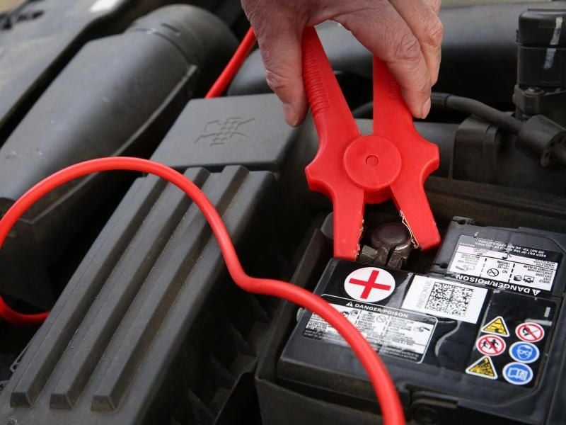 Bei der Starthilfe wird zuerst der Pluspol des Spenderautos mit dem Pluspol des Pannenwagens verbunden. Dann wird das schwarze Kabel an den Minuspol des Spenderautos angeschlossen. Foto: Bodo Marks/dpa-tmn