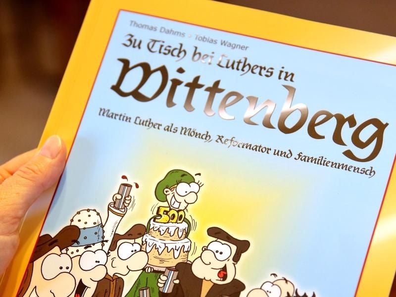 Eine Frau hält den Comic "Zu Tisch bei Luthers in Wittenberg" in den Händen. Foto: Jan Woitas