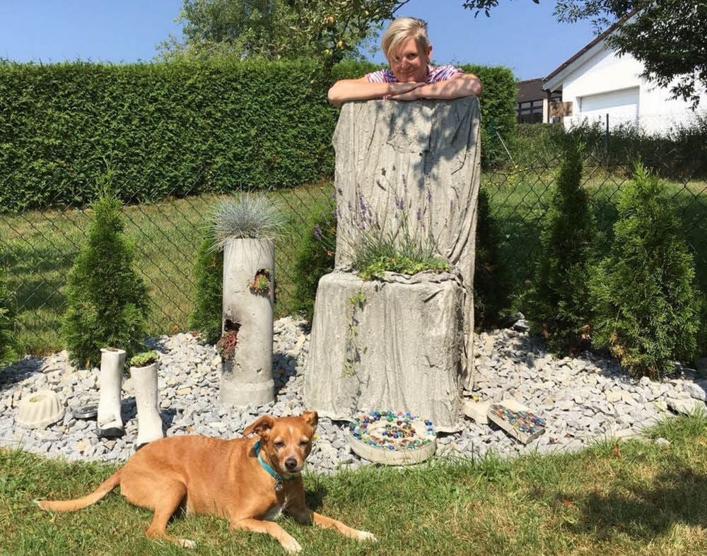 Michaela Lorenz mit Hund Timi in ihrem Hausgarten in Vilshofen, den sie mit selbst gegossenen Betonelementen gestaltet hat.