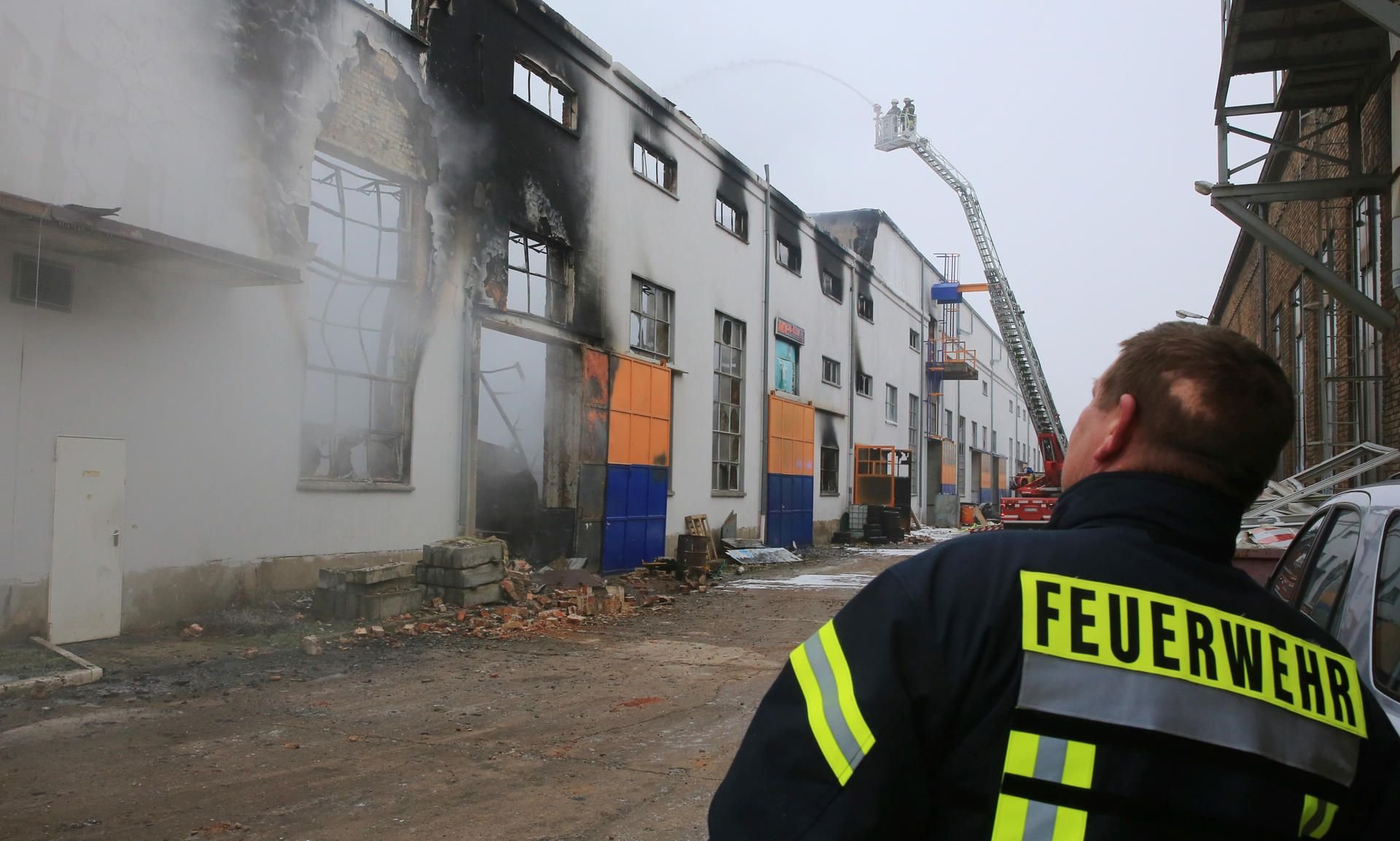 Ein Feuerwehrmann steht in Magdeburg vor einer ausgebrannten Lagerhalle.