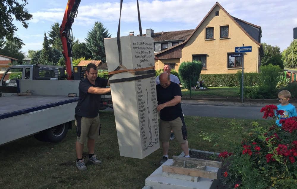 Mit einem Kran wird der Gedenkstein auf den Sockel gehoben - Markus (li.) und Harald Voigt richten ihn aus.