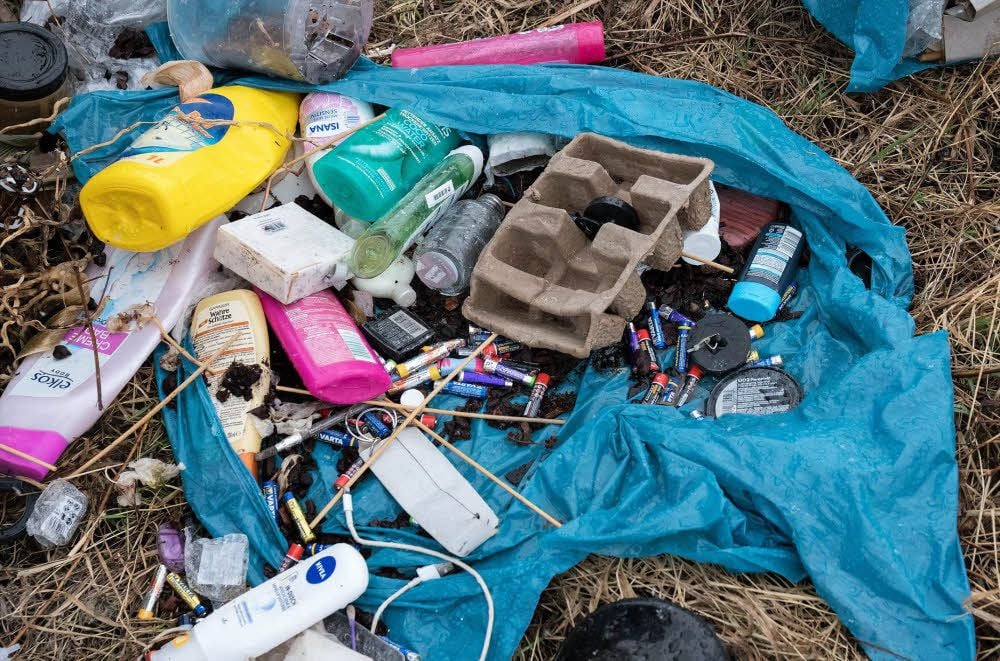 Ein aufgeplatzter Plastiksack mit Haushaltsabfall liegt in der Landschaft. Zumindest den Plastikmüll hätte der Besitzer ohne großen Aufwand in seiner gelben Tonne entsorgen können.