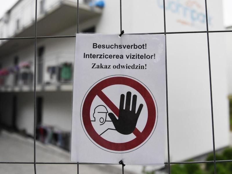"Besuchsverbot!" steht auf deutsch, rumänisch und polnisch auf einem Zettel an einem Bauzaun, der die Wohngebäude eines Betriebes umzäunt. Foto: Angelika Warmuth/dpa