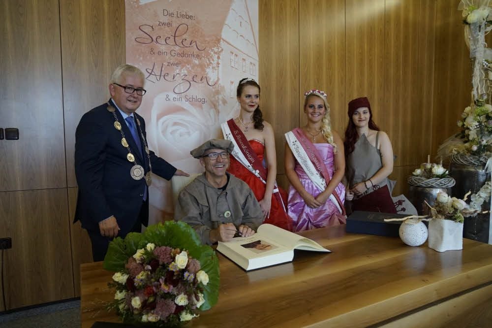 Steffen Rüdiger trägt sich ins Goldene Buch der Stadt ein. Oberbürgermeister Ralf Poschmann und die drei Majestäten - Rosenkönigin, Rosenprinzessin und RoseMarie - wohnen der feierlichen Zeremonie bei.
