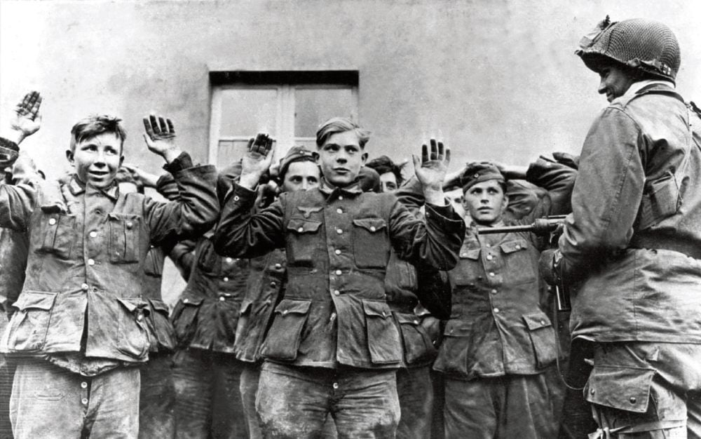 Als der Krieg nach Deutschland kam: Ein amerikanischer GI bewacht junge Wehrmachtssoldaten nach ihrer Gefangennahme durch die US-Armee.