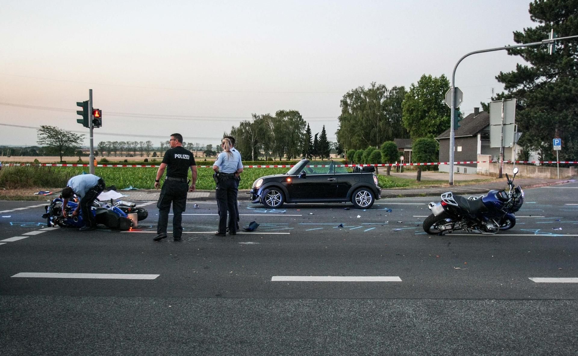 Polizisten sichern eine Unfallstelle mit zwei Motorrädern und einem PKW. Eine 53-jährige Motorradfahrerin ist bei einem Unfall nahe Kreuzau (Kreis Düren) ums Leben gekommen.