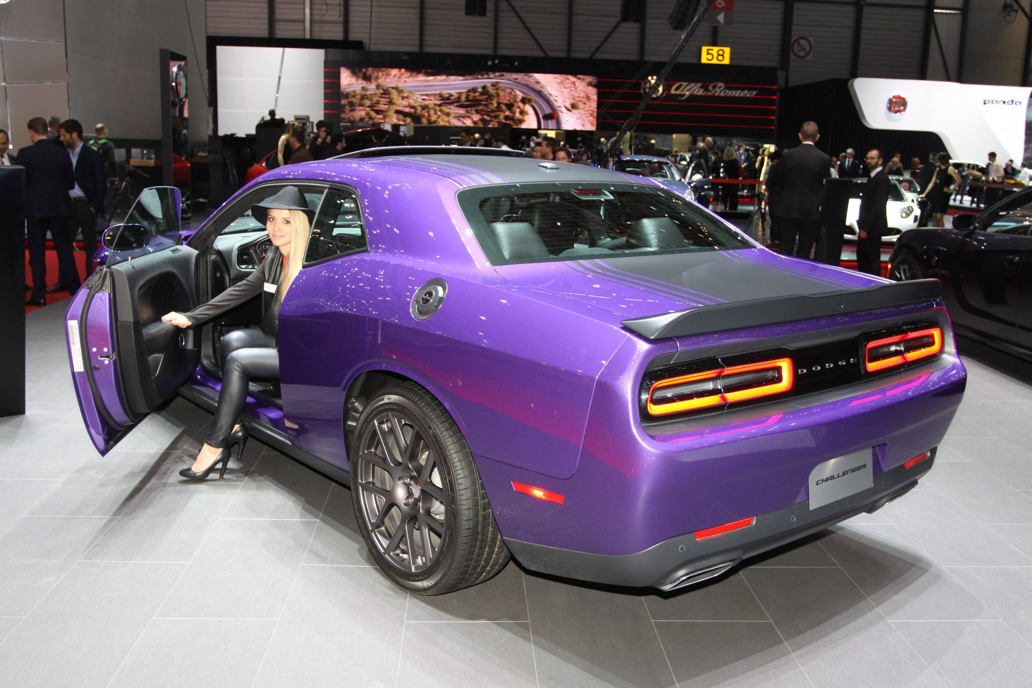 Eine Messehostess sitzt in einem lilafarbenen Dodge Challenger R/T, 86 beim Internationalen Auto Salon Genf.
