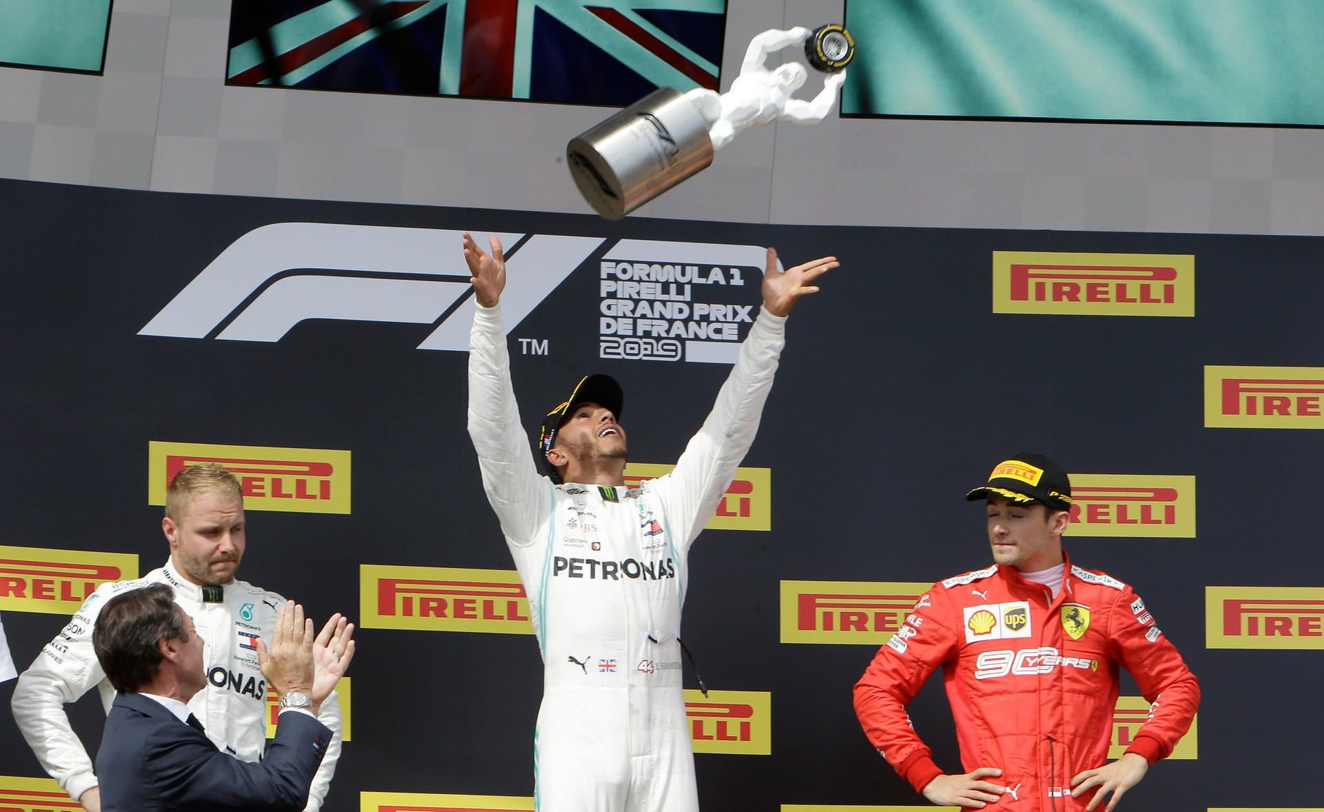 Sieger Lewis Hamilton wirft neben dem Zweitplatzierten Valtteri Bottas (l) und dem Drittplatzierten Charles Leclerc die Trophäe während der Siegerehrung in die Luft.