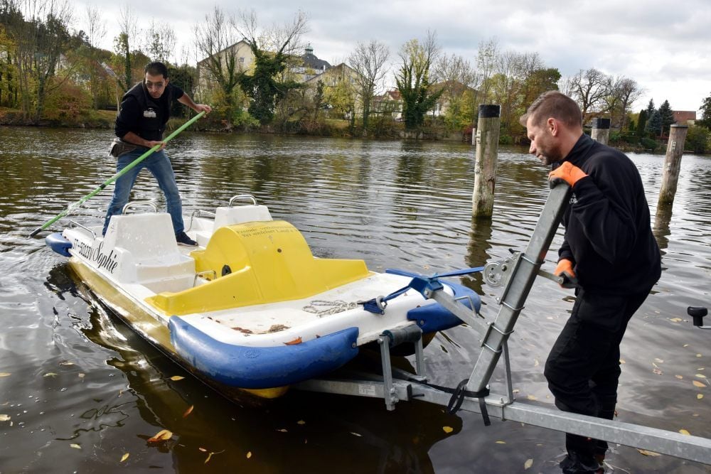 Die Boote werden aus der Saale gehoben und eingelagert. Im Bild Alexander Kleine (rechts) und Mahammad Fawaz beim Transport der Boote.