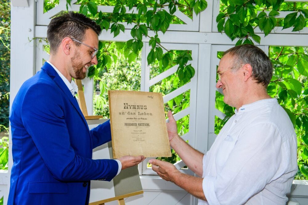 Ralf Eichberg (r.), Leiter des Nietzsche-Dokumentationszentrums, freut sich mit Daniel Wahrenberg, Chef der Naumburger Fielmann-Filiale, über die Partitur.