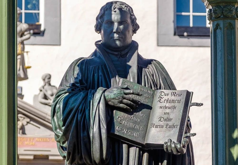Martin Luther, wie er als Denkmal - und als solches bereits vor einigen Jahren saniert - auf dem Wittenberger Marktplatz steht, rechts neben Melanchthon.