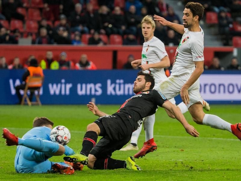Augsburgs-Keeper Andreas Luthe (l) prallt mit Leverkusens Kevin Volland (M) zusammen. Foto: Rolf Vennenbernd
