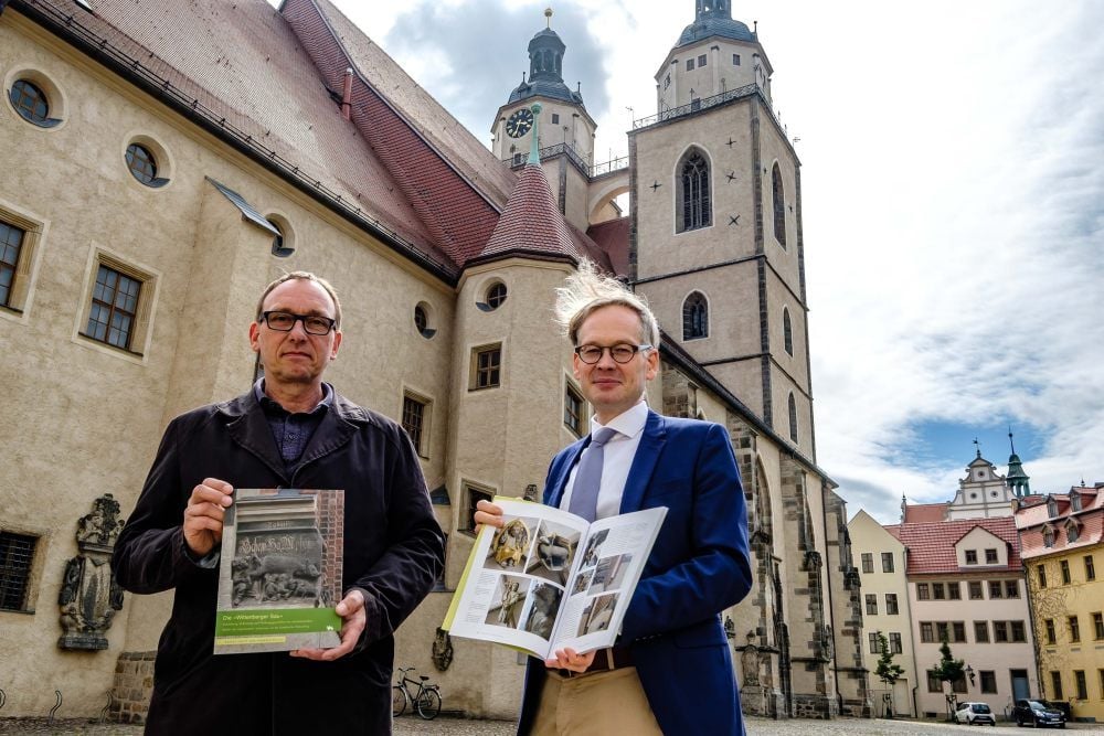 Jörg Bielig (links) und Johannes Block vor der Stadtkirche Wittenberg mit einer neuen Publikation zum Schandmal „Judensau“