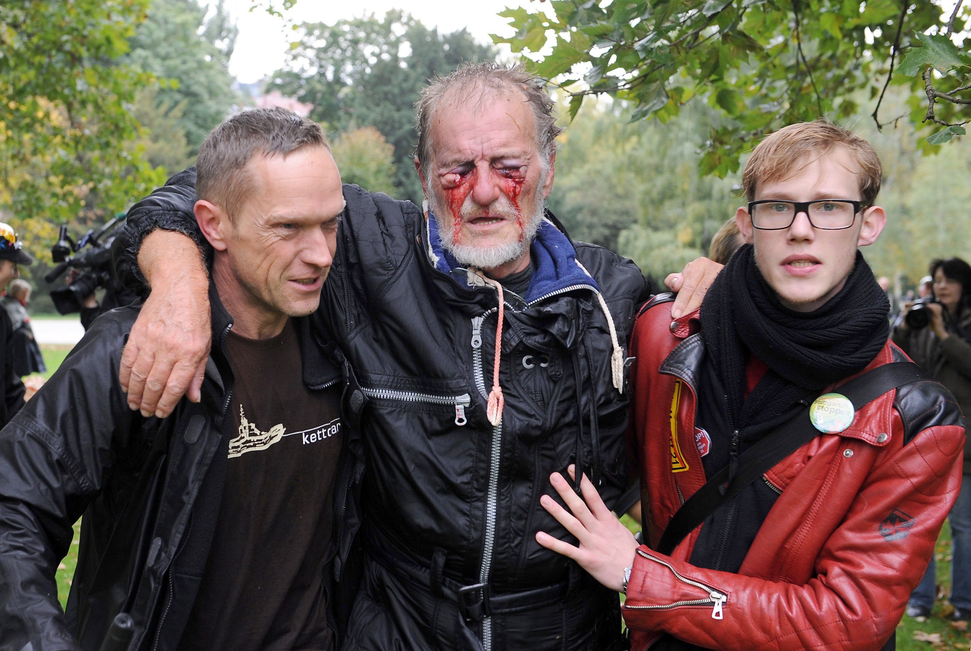 Zwei Männer stützen den durch Wasserwerfer verletzten Dietrich Wagner nach einer Demonstration gegen das Bahnprojekt Stuttgart 21 im Jahr 2010.