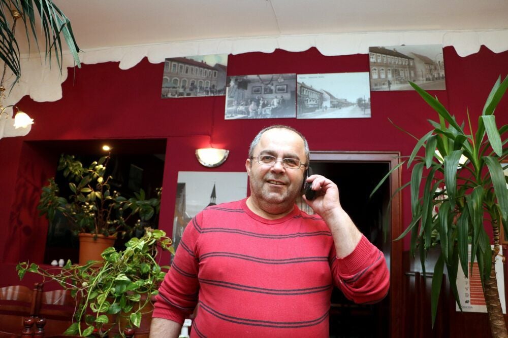 Das Telefon ist derzeit ein besonders wichtiges Arbeitsmittel für Malekas Athanasios, Inhaber vom Restaurant Herkules in Jessen. So erhält er Aufträge für Außer-Haus-Bestellungen. Die Zwangsschließzeit der Gaststätte wird auch genutzt, um das Lokal zu renovieren und neu zu gestalten (im Hintergrund Fotografien von der Gaststätte, wie sie früher mal aussah) sowie Stühle und Sitzbänke zu erneuern.