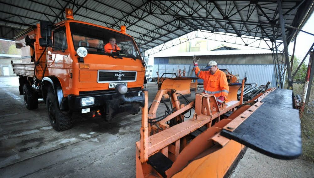 Für alle Fälle: Beim Stadthof Bitterfeld-Wolfen laufen die Vorbereitungen - Mitarbeiter befestigen ein Schneeschild an einem Lkw.