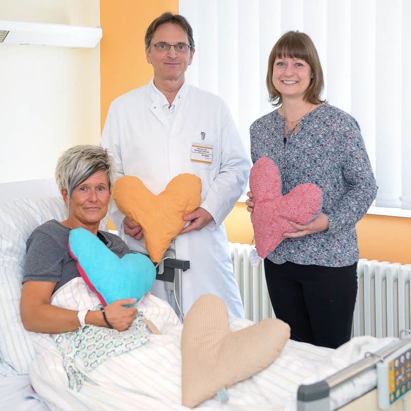 Mit viel Herz: Patientin Kristina Baer und Professor Christoph Thomssen (v. l.) freuen sich über die von Daniela Müller (r.) mit Liebe genähten Herzen für Brustkrebspatienten.