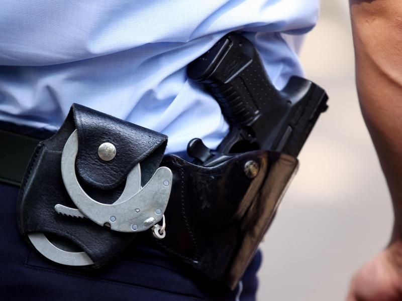 Ein Polizist mit Handschellen und Pistole am Gürtel. Foto: Oliver Berg/Archiv