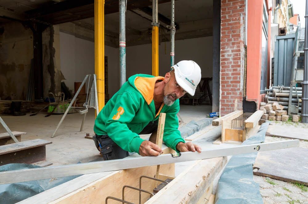Vorarbeiter Heiner Junge von der Oberlichtenauer Baugesellschaft mbH arbeitet auf der Vorderseite des Hauses an der Betonverschalung.