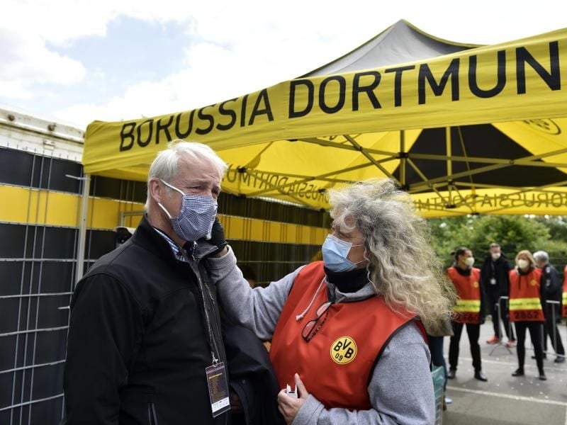 Beim Mitglied einer TV-Crew wird vor dem Einlass ins Stadion die Temperatur gemessen. Foto: Martin Meissner/AP-Pool/dpa