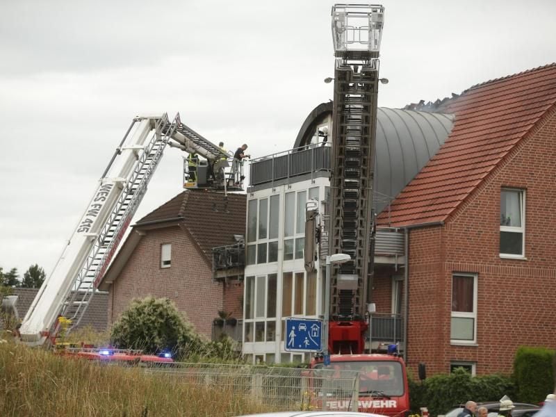 Feuerwehrleute nähern sich dem beschädigten Wohnhaus mit einer Drehleiter. Foto: David Young/dpa