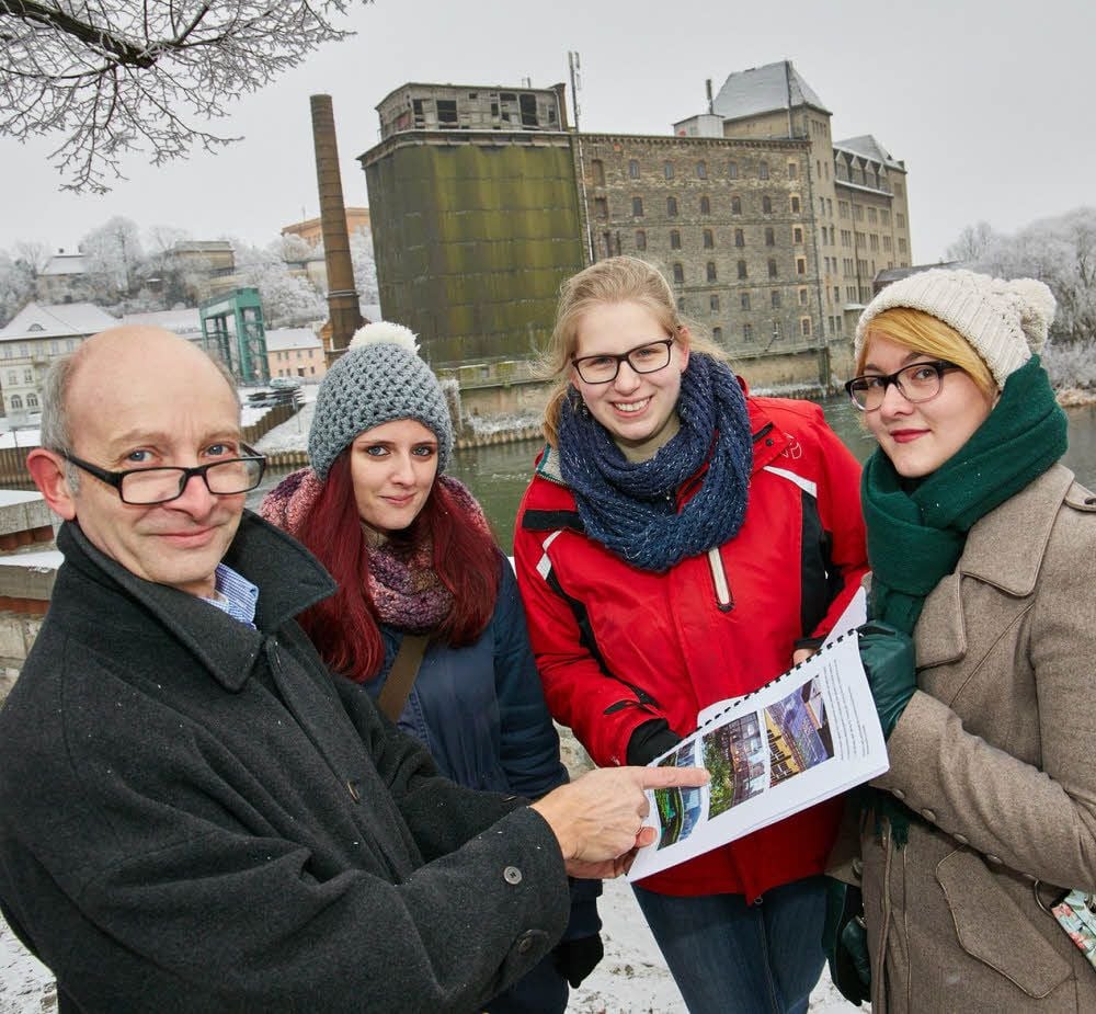 Heinrich Haass (von links) und die Studentinnen Melanie Schreier, Johanna von Butler und Sophia Böttcher vor der Kulisse der alten Mühle, für die sie Kleingarten-Parzellen auf dem Dach vorschlagen.