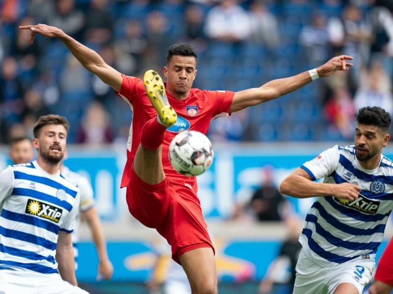 Heidenheims Robert Glatzel (M)und die Duisburger Dustin Bomheuer (l) und Enis Hajri versuchen an den Ball zu kommen. Foto: Bernd Thissen