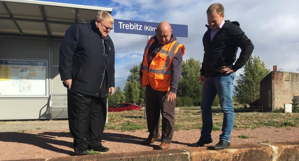 Ronald Mormann (v.l.), Peter Zbyszewski und Martin Zbyszewski stehen an der funktionstüchtigen Bahnsteigkante des Bahnhofes Trebitz.