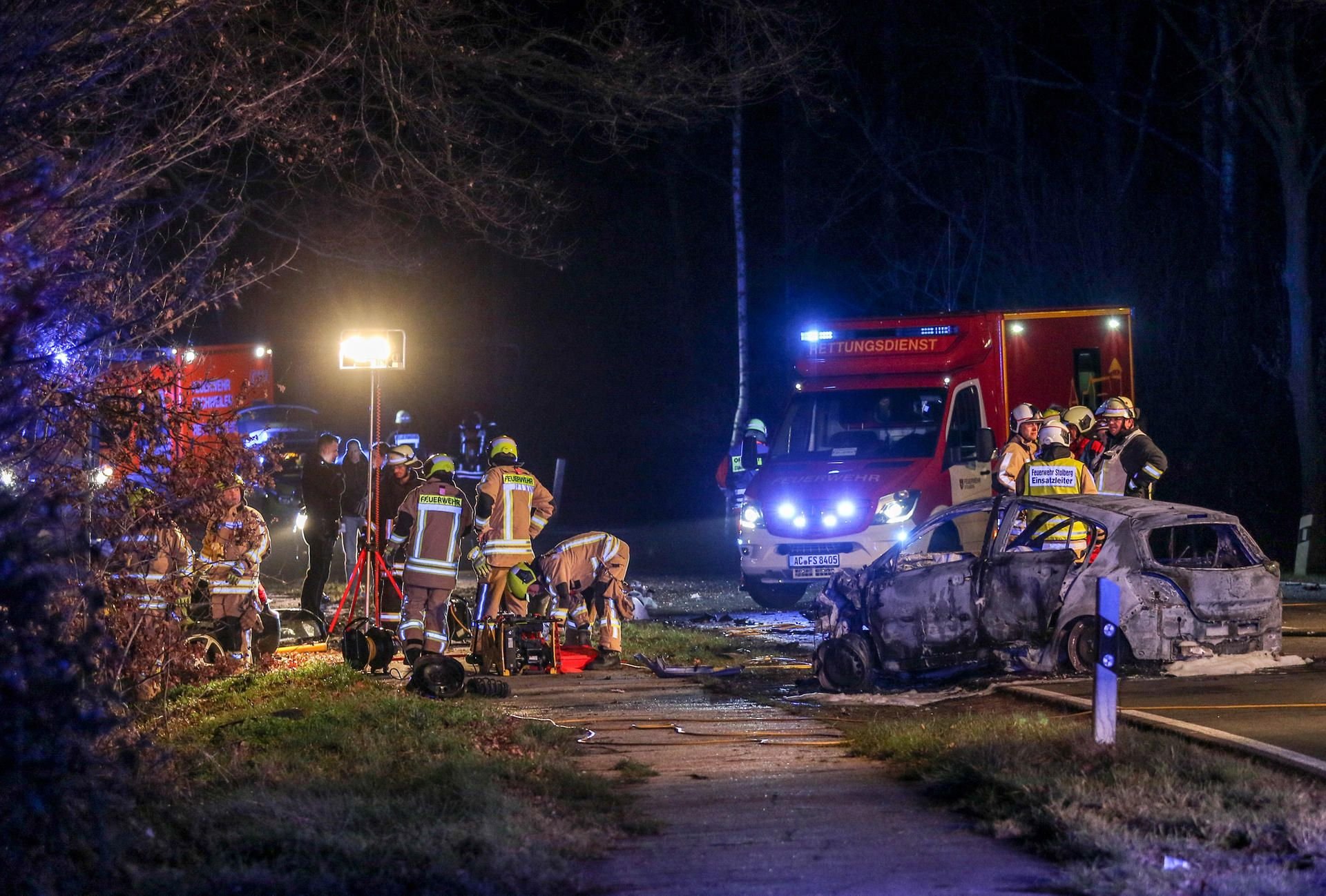 Feuerwehrleute stehen in der Nacht zu Samstag auf einer Landstraße in Stolberg bei Aachen an zwei Fahrzeugen, die frontal zusammengestoßen waren.
