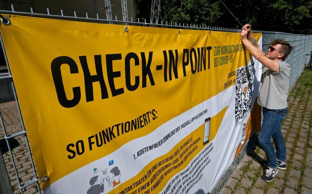 Pierre Gehrmann bringt auf der Peißnitz ein Banner für eine neue App an. Mit dieser können sich Konzertbesucher schnell und sicher registrieren.