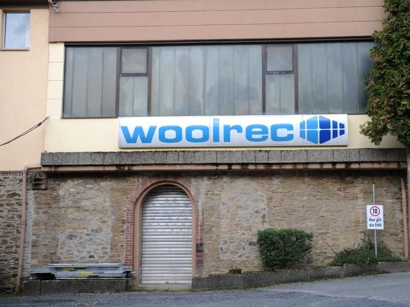 Ein Firmenschild auf einem Gebäude der Firma Woolrec. Foto: Arne Dedert/dpa/Archivbild