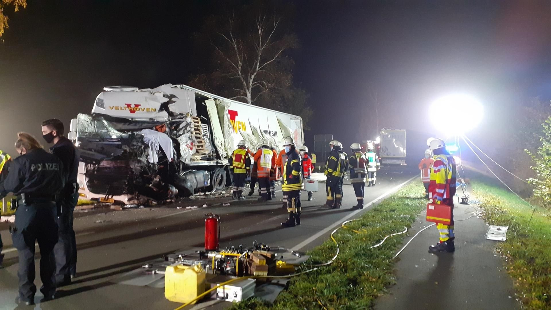Polizisten und Feuerwehrleute stehen nach einem Unfall auf der B6 an einem schwer beschädigten Laster. Bei der Kollision von zwei Lkw wurde einer der Fahrer getötet.