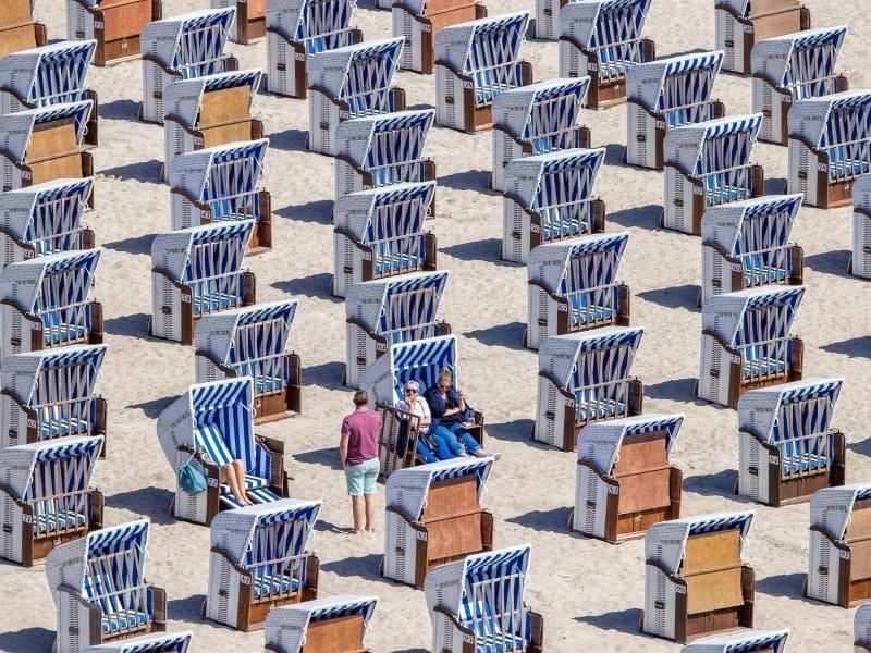 Erste Urlauber sitzen in Strandkörben am Ostseestrand in Warnemünde. Foto: Jens Büttner/dpa-Zentralbild/dpa