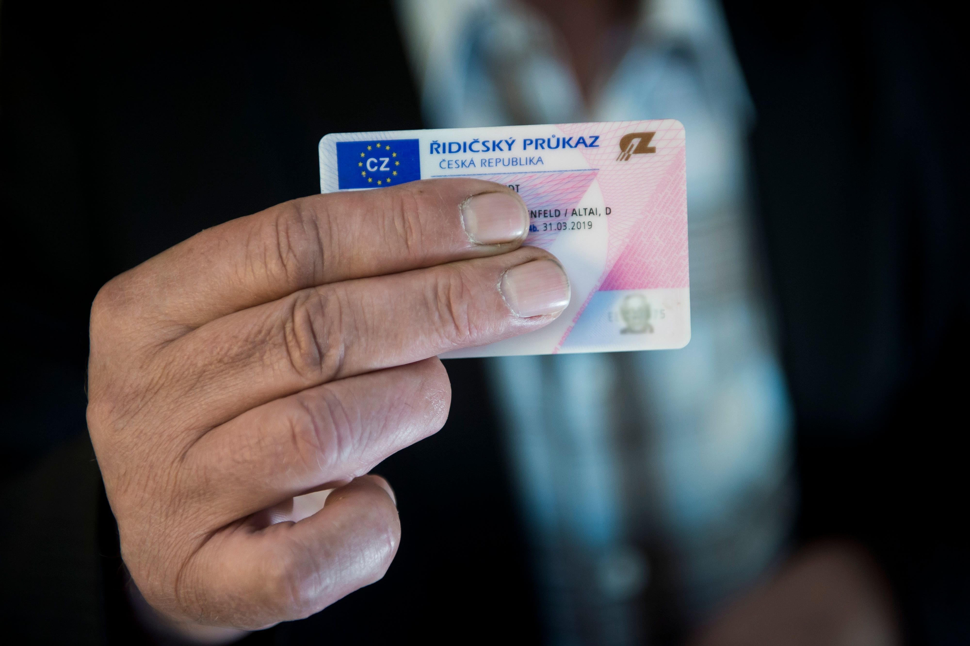 Ein Mann hält seinen tschechischen Führerschein in der Hand