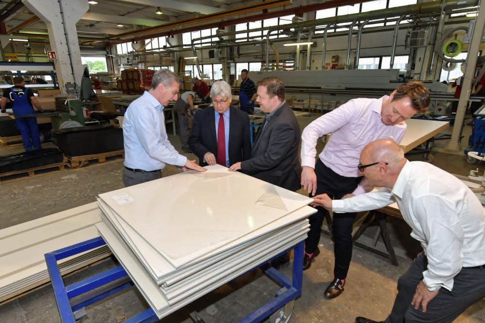 Hufcor-Produktionsleiter Barnutz (l.) und Geschäftsführer de Pater (2.v.r.) zeigen Bürgermeister Kuras (2.v.l.) das neue Oberflächenmaterial.