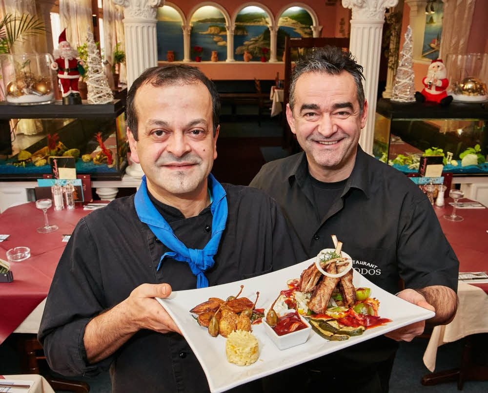 Seit vielen Jahren ein gutes Team: Küchenchef Dimitrios Chitos (links) und Adam Tolias präsentieren Lammkrone nach „Rhodos“-Art.